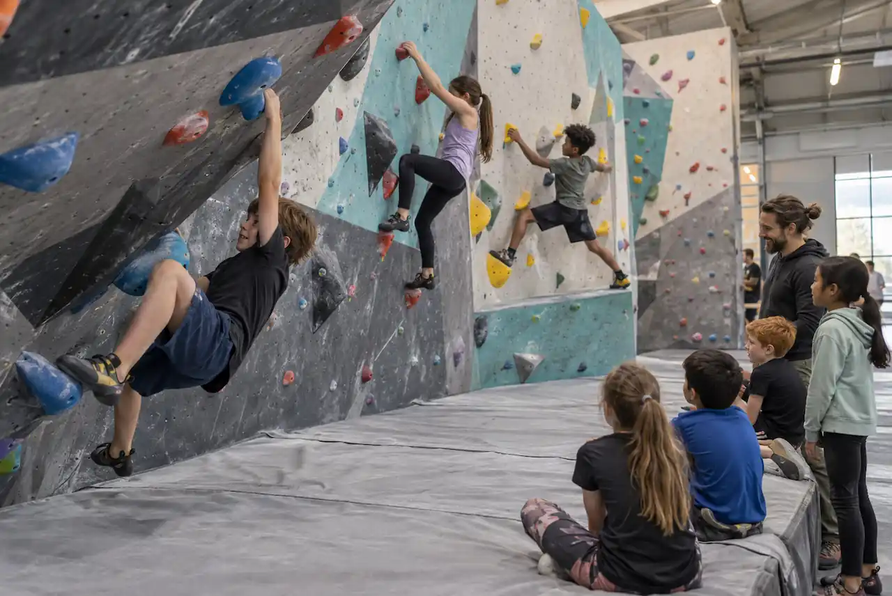 Children trying bouldering challenges at an indoor birthday party